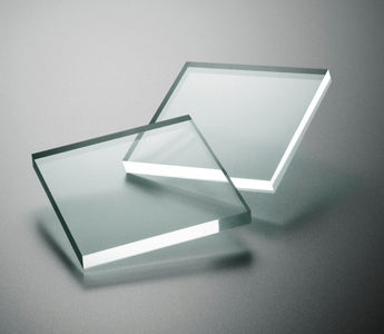 Square pieces of transparent acrylic sheeting on a gray background