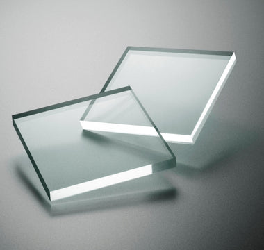 Square pieces of transparent acrylic sheeting on a gray background